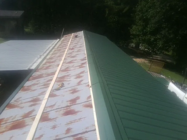 Old rusted panels beside newly installed green metal roofing — Wind Damage Roof Repair by Roofing Brothers in Dallastown