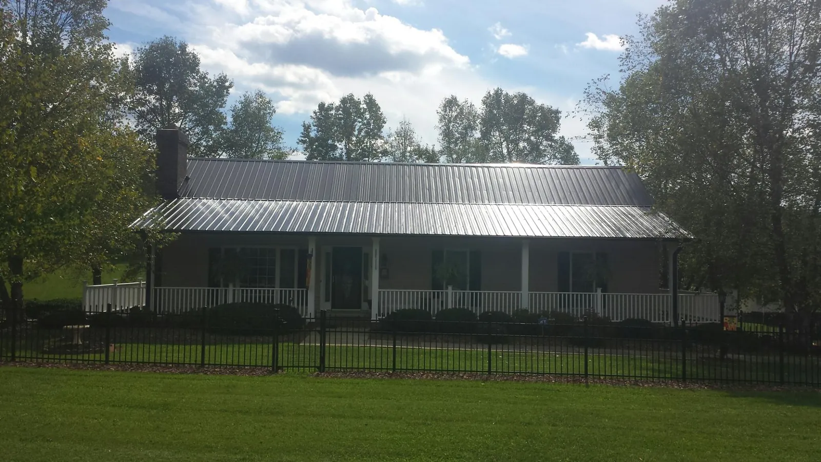 Gray metal roof on a brick ranch with a full width front porch — Gutter Guard Installation work by our crew in Dallastown
