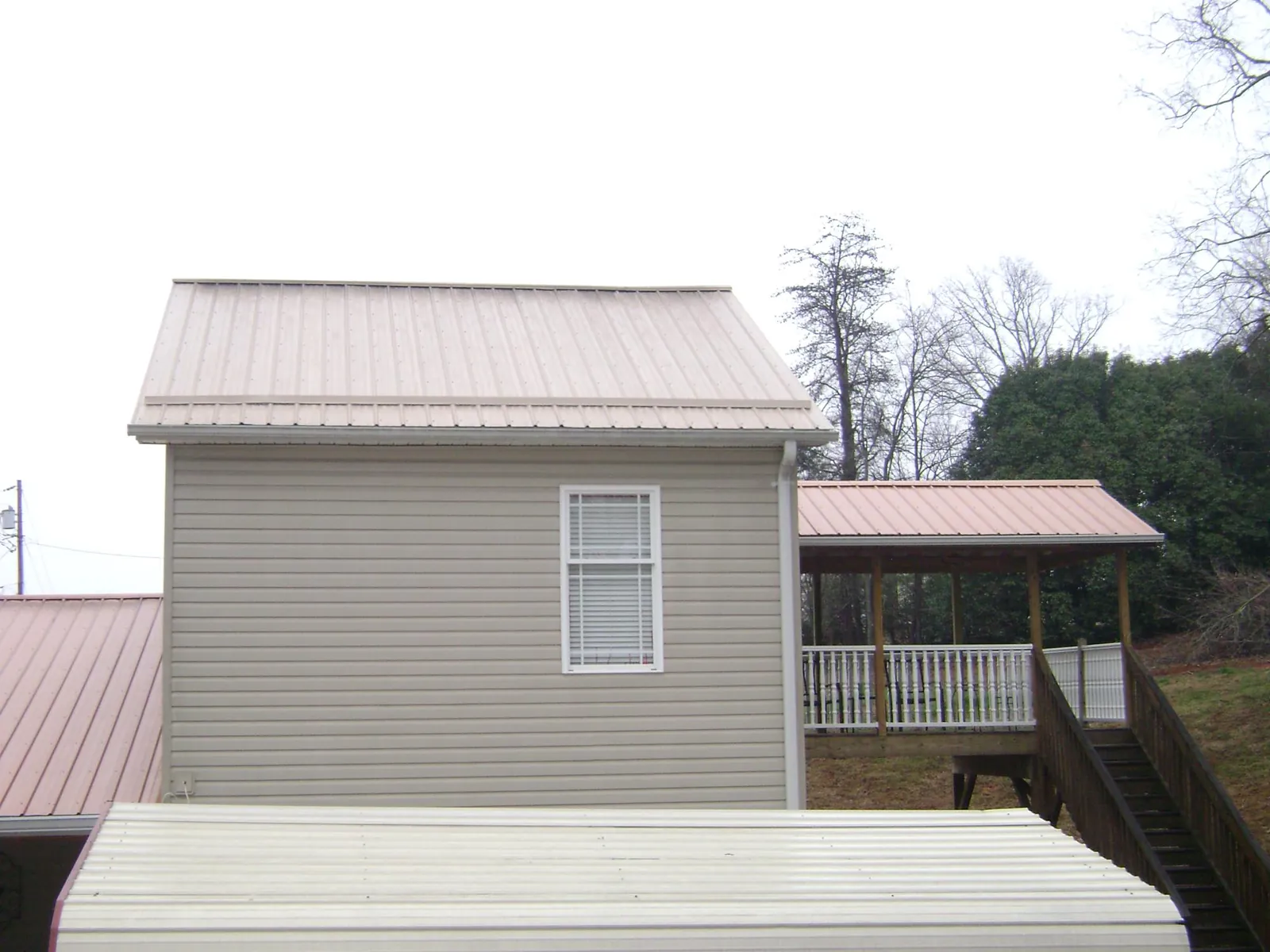Tan metal roofs on a two story addition and attached porch, from a Roof Replacement job in Dallastown