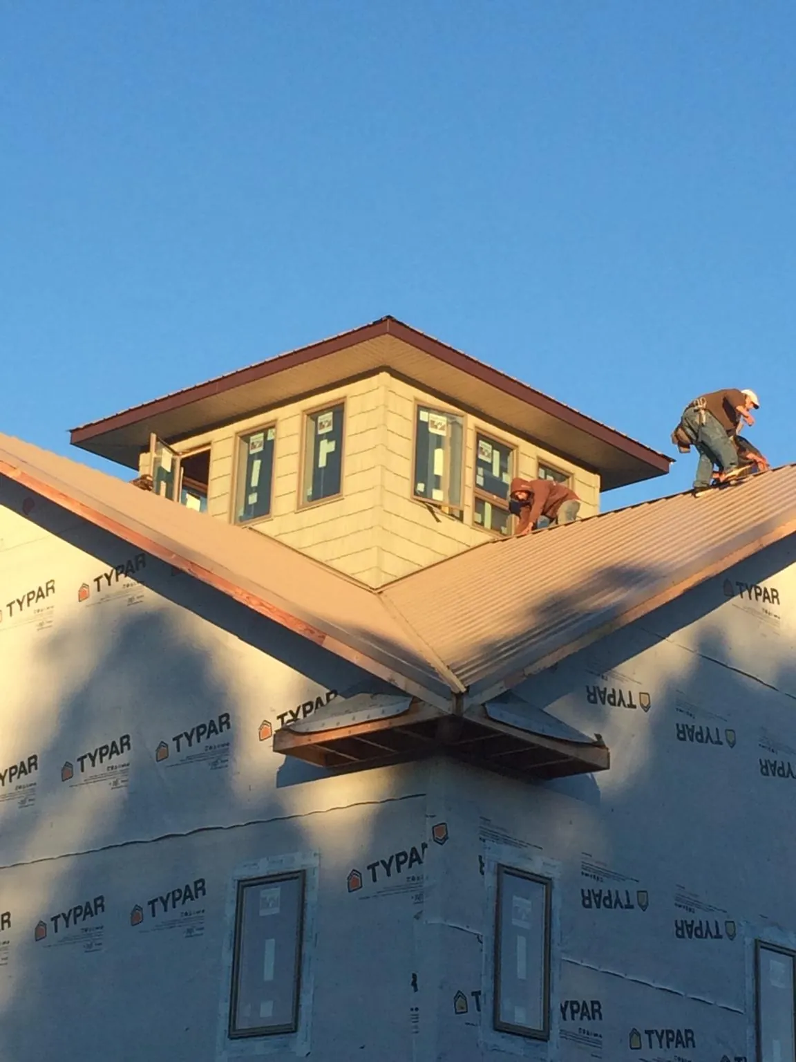 Roofers working around a rooftop cupola on a new metal roof at sunset — Roof Waterproofing in Dallastown by Roofing Brothers